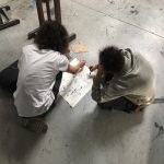 Dwie postaci kucające pracują nad stworzeniem kolektywnego rysunku