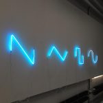 Seria drgających neonów świecących na niebiesko przedstawiająca podstawowe formy fal dźwiękowych.
