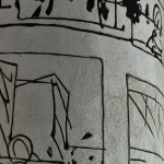 Sgraffito czarno-białe na szerokim słupie. Czarne ryte linie przedstawiają kolaż ze szkiców Andrzeja Wajdy - kadr