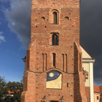 zegar słoneczny autorstwa Marcina Bogusławskiego wykonany w technice sgraffito trójbarwnego ze złoceniami. Widok na wieżą. Oprócz podziałki godzinowej, przedstawione są znaki zodiaku i popiersie Mikołaja Kopernika.
